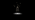 A still image from a multimedia artwork, showing a sculpture on a dark background with birds flying above it.